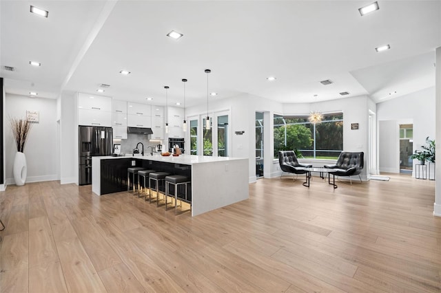 kitchen featuring a wealth of natural light, a center island with sink, white cabinets, and light hardwood / wood-style floors