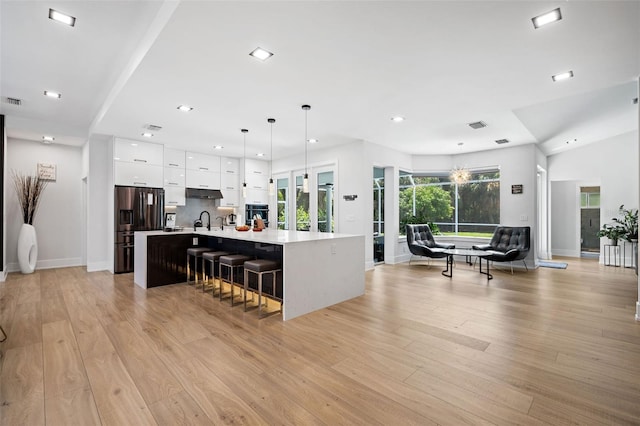 kitchen featuring a center island with sink, light hardwood / wood-style flooring, a breakfast bar area, and hanging light fixtures