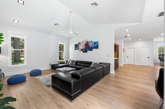 living room with ceiling fan, light hardwood / wood-style floors, and vaulted ceiling