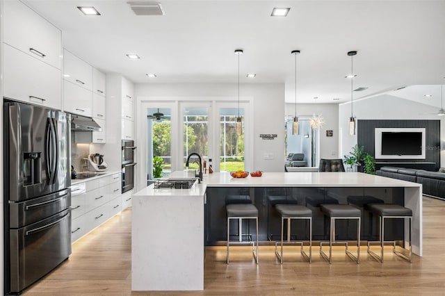 kitchen with light wood-type flooring, a large island, black electric cooktop, stainless steel fridge with ice dispenser, and a breakfast bar