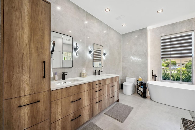 bathroom with toilet, a tub, vanity, tile walls, and concrete flooring