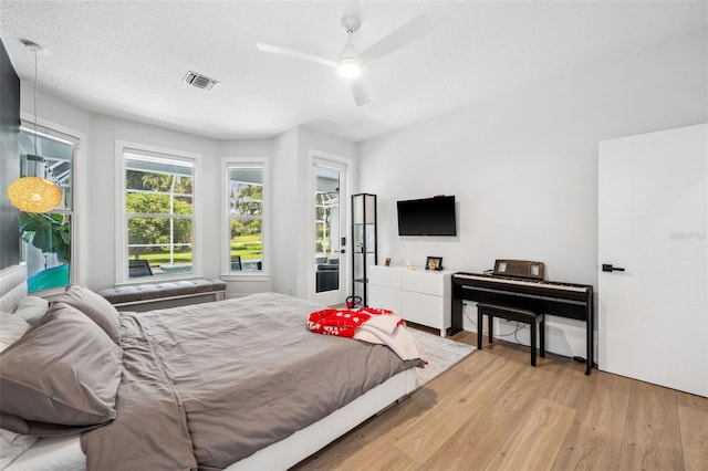 bedroom with ceiling fan, a textured ceiling, and light hardwood / wood-style flooring