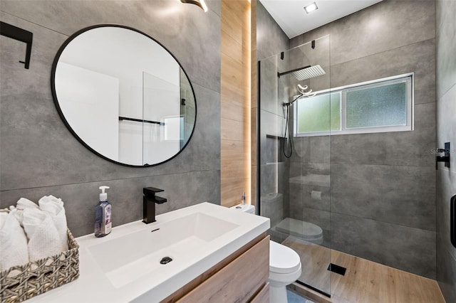 bathroom with toilet, a tile shower, hardwood / wood-style flooring, and vanity