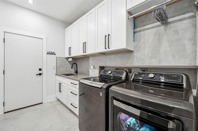 laundry area with independent washer and dryer, cabinets, sink, and light tile patterned floors