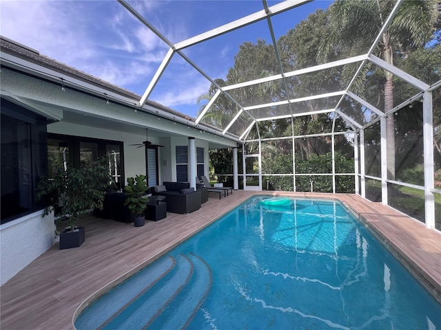 view of swimming pool with an outdoor living space, glass enclosure, a deck, and ceiling fan