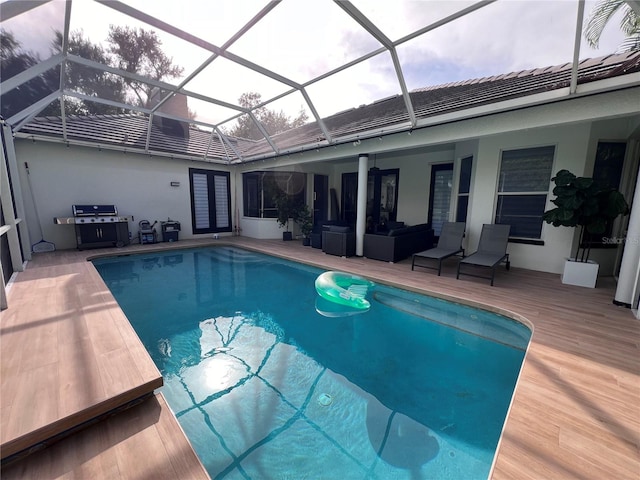 view of pool with grilling area, a patio area, and glass enclosure