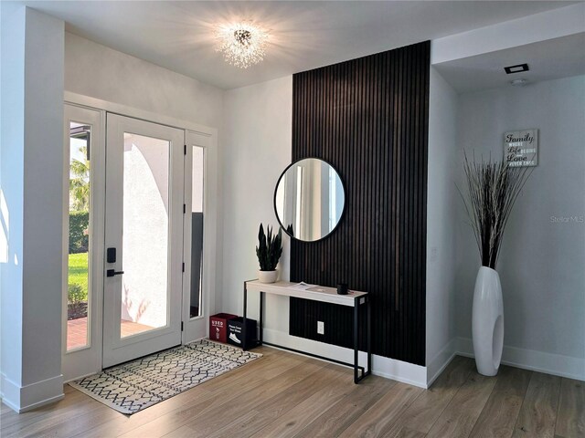 entryway featuring baseboards, wood finished floors, and a notable chandelier