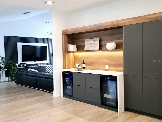 bar with beverage cooler, lofted ceiling, a dry bar, and light wood-type flooring