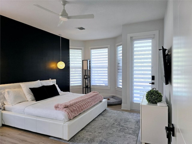 bedroom with ceiling fan, multiple windows, visible vents, and light wood-type flooring
