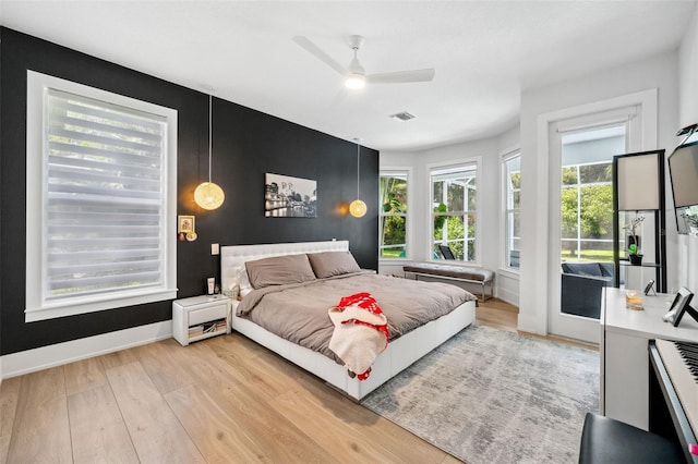 bedroom featuring light wood finished floors, access to exterior, baseboards, visible vents, and a ceiling fan