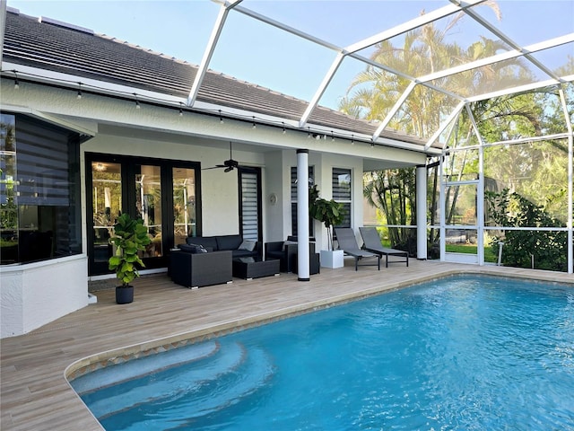 outdoor pool with an outdoor living space, a deck, glass enclosure, and a ceiling fan