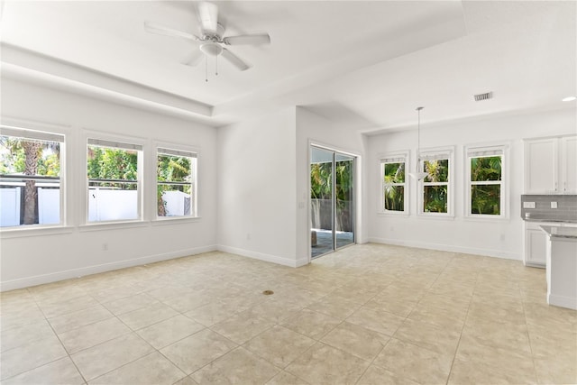 unfurnished living room with a raised ceiling, light tile patterned floors, and ceiling fan