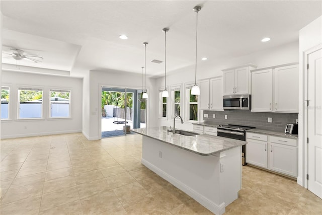 kitchen with pendant lighting, a center island with sink, sink, white cabinetry, and appliances with stainless steel finishes