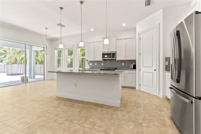 kitchen with white cabinets, pendant lighting, appliances with stainless steel finishes, and an island with sink