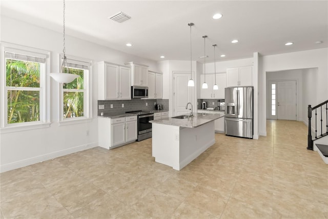 kitchen featuring stainless steel appliances, white cabinets, and a kitchen island with sink