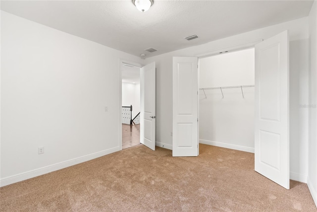 unfurnished bedroom featuring a closet and light colored carpet