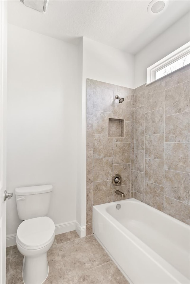 bathroom featuring toilet and tiled shower / bath combo