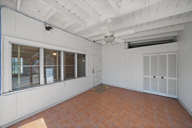 tiled empty room featuring ceiling fan, beamed ceiling, and wooden ceiling