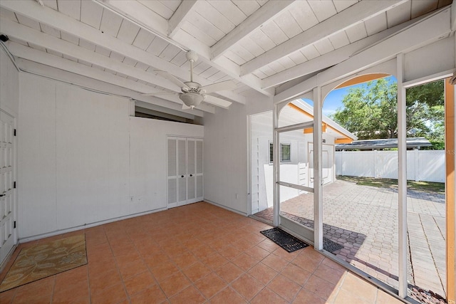 tiled empty room featuring beam ceiling and ceiling fan