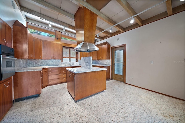 kitchen with island exhaust hood, backsplash, stainless steel oven, and track lighting