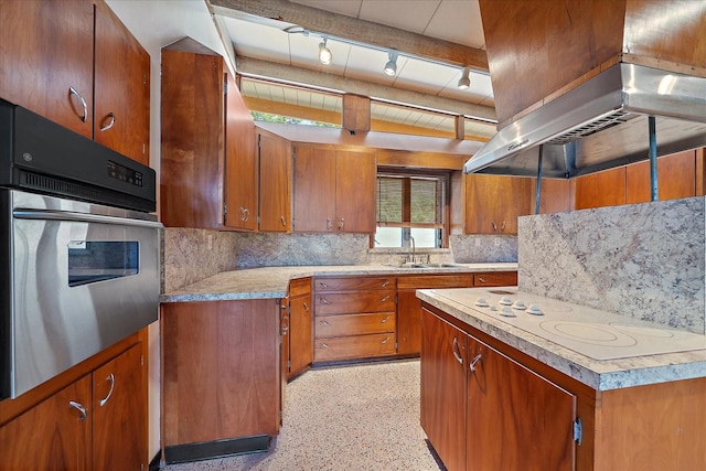 kitchen with sink, backsplash, wall chimney range hood, stainless steel oven, and track lighting