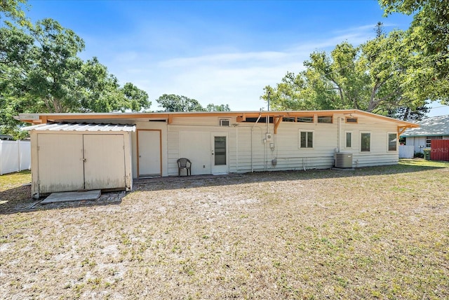 back of house with central AC unit and a lawn