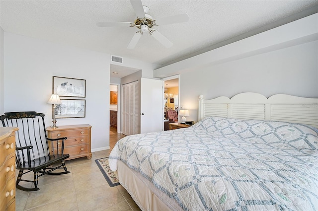 bedroom featuring ceiling fan, a closet, a textured ceiling, and light tile floors