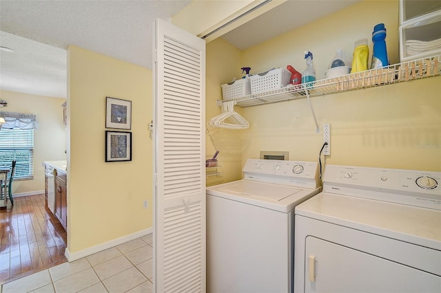 clothes washing area with washer and clothes dryer, light hardwood / wood-style flooring, and a textured ceiling