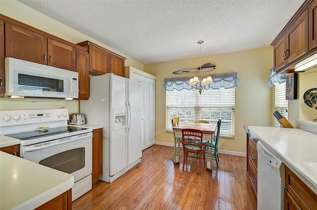 kitchen featuring plenty of natural light, decorative light fixtures, an inviting chandelier, and white appliances