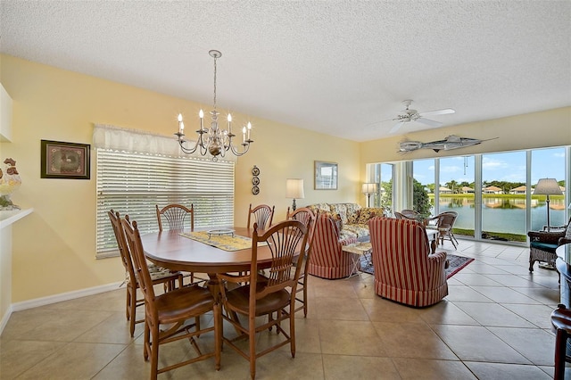 dining room featuring tile flooring, ceiling fan with notable chandelier, a water view, and a textured ceiling