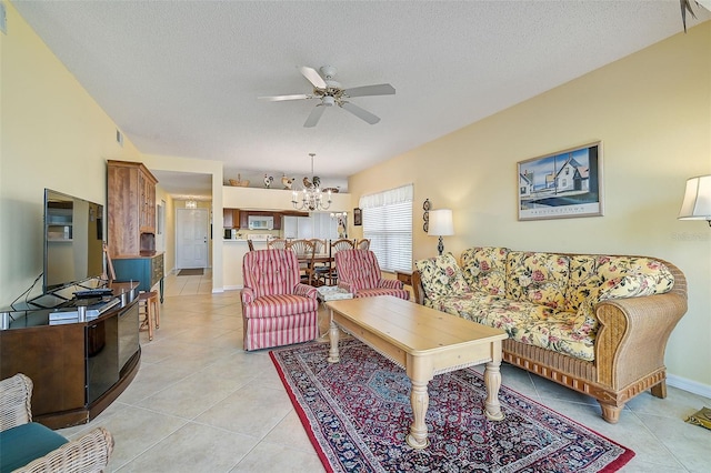 living room featuring a textured ceiling, light tile floors, and ceiling fan with notable chandelier