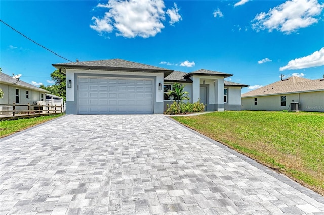 view of front of property featuring a front yard, a garage, and central AC unit