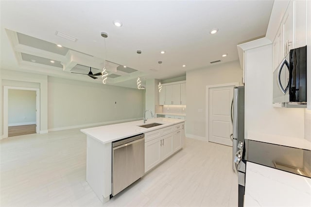 kitchen with appliances with stainless steel finishes, a center island with sink, ceiling fan, coffered ceiling, and white cabinetry