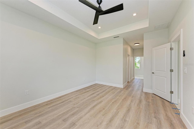 unfurnished bedroom with light hardwood / wood-style flooring, ceiling fan, and a tray ceiling