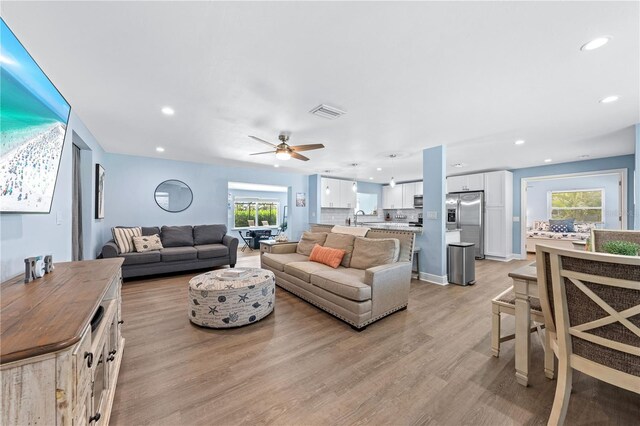 living room featuring light wood finished floors, visible vents, a ceiling fan, and recessed lighting