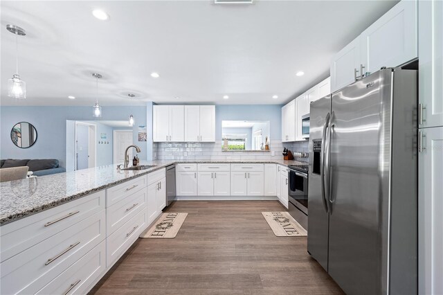 kitchen with hanging light fixtures, appliances with stainless steel finishes, a sink, and white cabinets