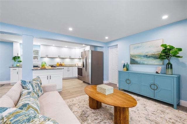 living area with baseboards, light wood-style flooring, and recessed lighting