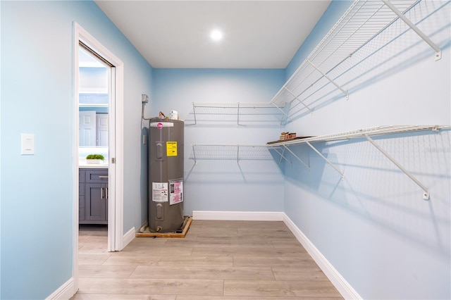 spacious closet featuring light wood-type flooring and electric water heater