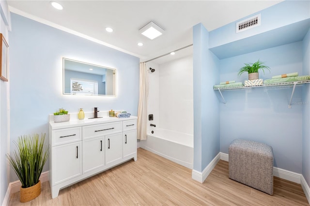 full bath with baseboards, visible vents, wood finished floors,  shower combination, and vanity