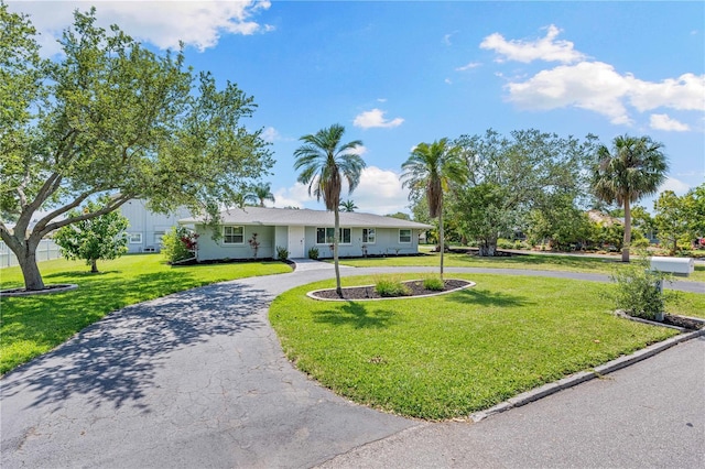 ranch-style home with a front yard and curved driveway