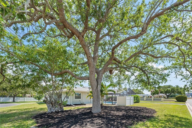 view of front of property with a front lawn, a lanai, and fence