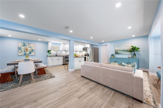 living area with light wood finished floors, baseboards, visible vents, and recessed lighting