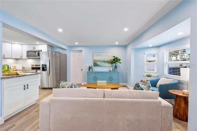 living room featuring light wood-style floors, baseboards, and recessed lighting