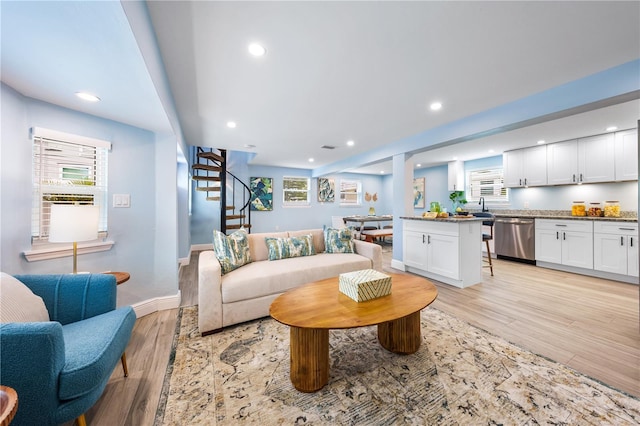 living room with a wealth of natural light, recessed lighting, light wood-style flooring, and stairs