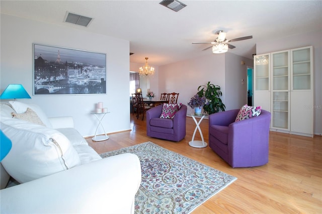 living room with hardwood / wood-style floors and ceiling fan with notable chandelier