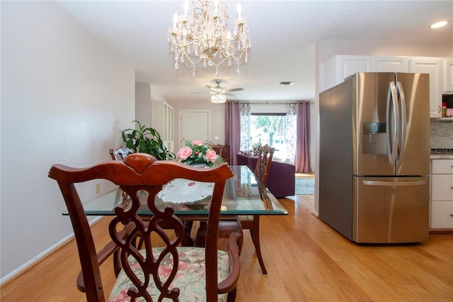 dining area featuring light hardwood / wood-style flooring and ceiling fan with notable chandelier