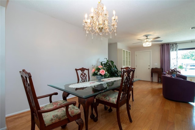 dining area featuring ceiling fan with notable chandelier and light wood-type flooring