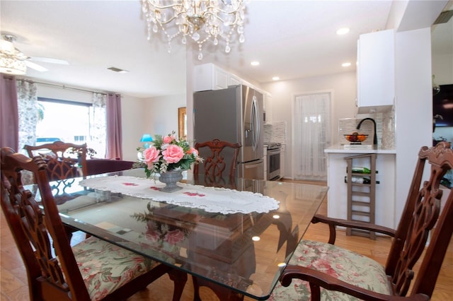 dining space with light wood-type flooring and ceiling fan with notable chandelier