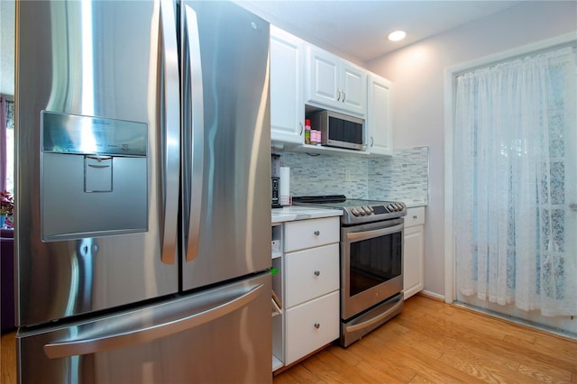 kitchen featuring backsplash, white cabinetry, light hardwood / wood-style flooring, and appliances with stainless steel finishes