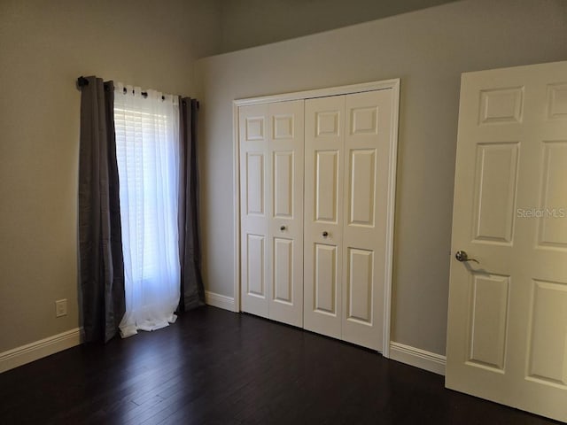 unfurnished bedroom with dark wood-type flooring and a closet